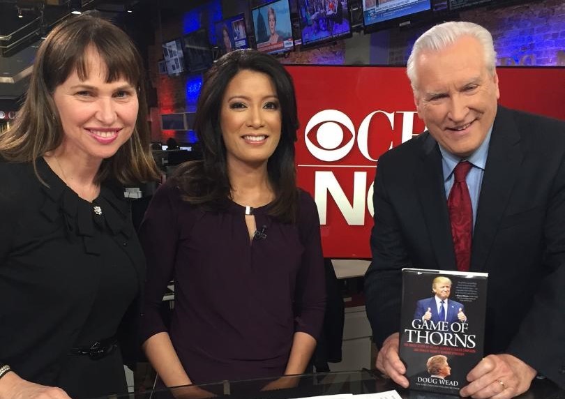 Author Doug Wead holds his book Game of Thorns standing next to Elaine Quijano and wife, Myriam on CBS News